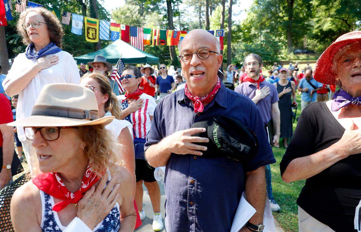 David Dodson, center, and the crowd recite the Pledge of Allegiance after the Watts-Hillandale neighborhood’s 72nd annual Fourth of July parade in Durham, N.C, Sunday, July 4, 2021. The parade participants gather after the parade to recite the Pledge of Allegiance, hear patriotic songs and drink a cold Coke in a little glass bottle.