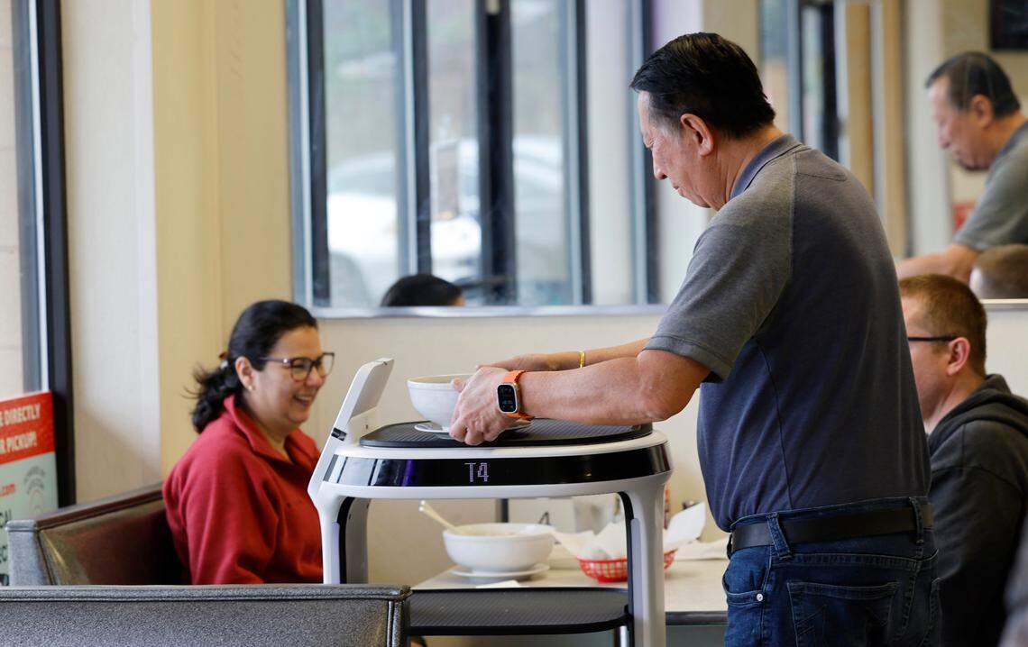 Michael Wongkittiroch, owner of Pho 919, serves dishes from a Servi Delivery Robot.