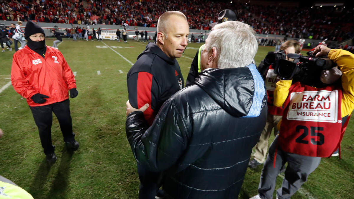 N.C. State head coach Dave Doeren greets North Carolina head coach Mack Brown after N.C. State’s 34-30 victory over UNC at Carter-Finley Stadium in Raleigh, N.C., Friday, November 26, 2021.