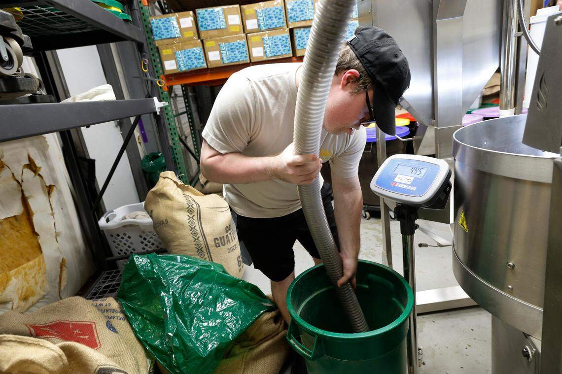 Paul Kocher uses a vacuum devise to transfer 26 lbs. of coffee beans to the roaster at 321 Coffee roasting facility in Raleigh, N.C., Tuesday, June 25, 2024.