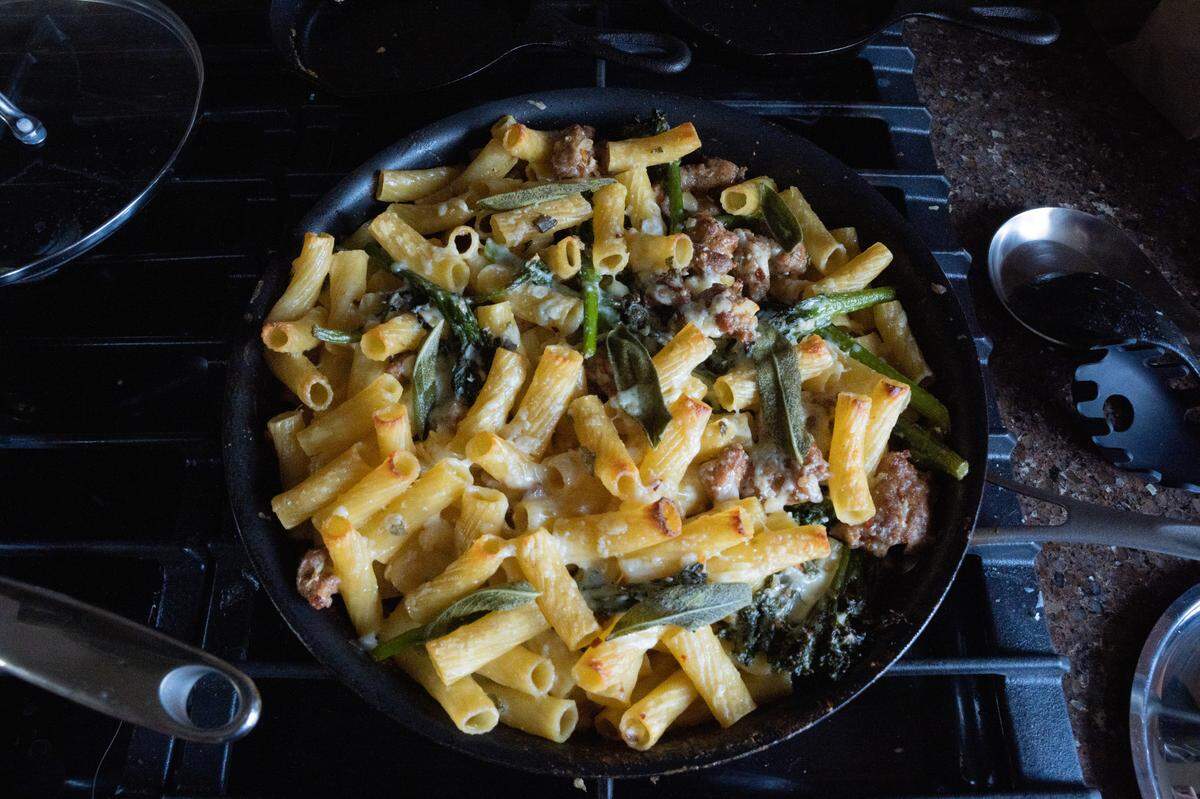 Baked pasta with sausage and broccoli in a skillet.