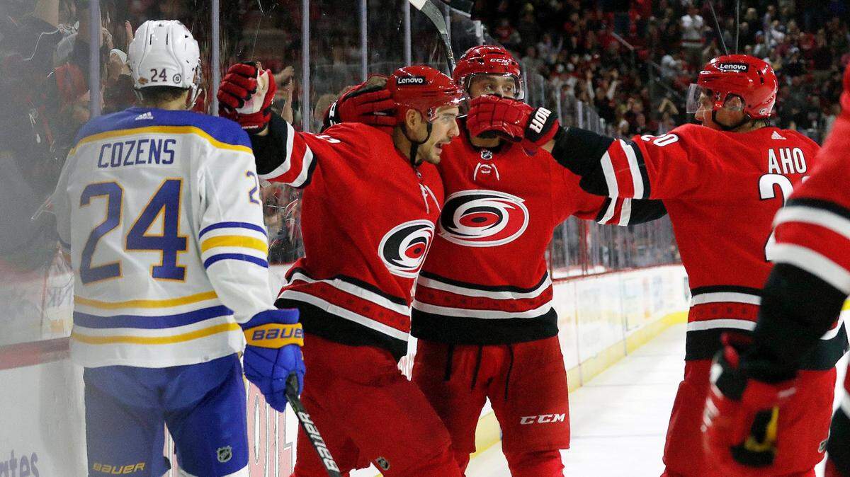 Carolina Hurricanes’ Nino Niederreiter (21) celebrates his goal with teammates Jalen Chatfield (64), and Sebastian Aho (20) as Buffalo Sabres’ Dylan Cozens (24) skates by during the second period of an NHL hockey game in Raleigh, N.C., Saturday, Dec. 4, 2021. (AP Photo/Karl B DeBlaker)