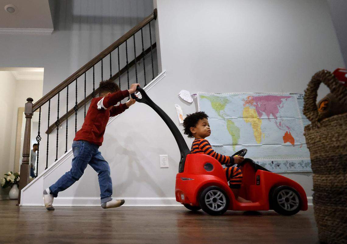 London Wasson, 4, pushes Channing Wasson, 1, in a toy car down the hallway of their home in Durham, N.C. on Wednesday, Dec. 7, 2022. The siblings were both home from childcare as they battled symptoms of upper respiratory illness.