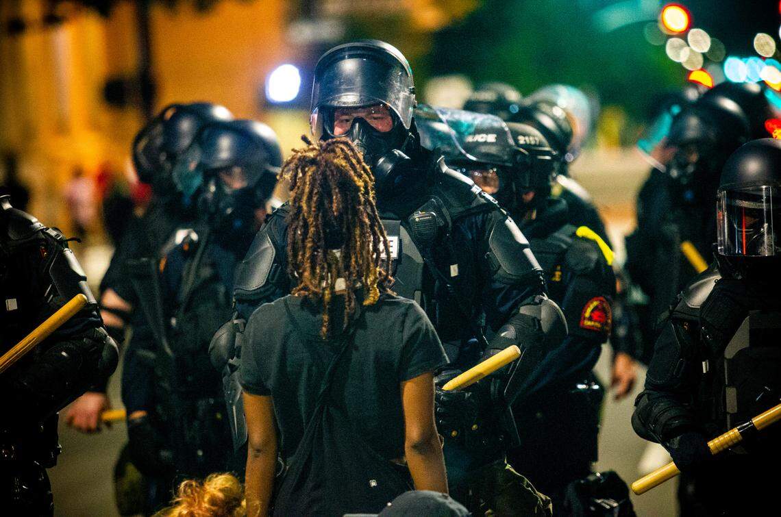 A protester faces off against police in riot gear outside the State Capitol during the second day of protests in Raleigh Sunday night May 31, 2020.