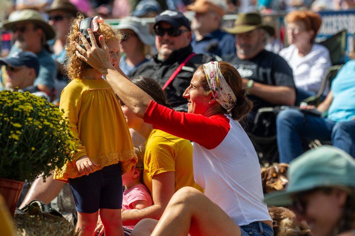 Susana Warner adjusts hearing protection for her 3-year-old daughter Emery Warner as the Chatham Rabbits perform outside the Duke Energy Center for the Performing Arts during the IBMA World of Bluegrass festival in downtown Raleigh Friday, Oct. 1, 2021.