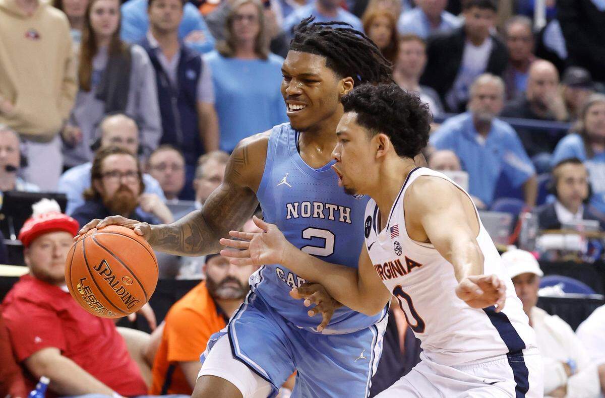 North Carolina’s Caleb Love (2) drives to the basket while defended by Virginia’s Kihei Clark (0) during the first half of UNC’s game against Virginia in the quarterfinals of the ACC Men’s Basketball Tournament in Greensboro, N.C., Thursday, March 9, 2023.