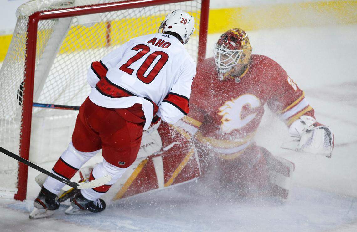 Carolina Hurricanes’ Sebastian Aho, left, scores the on Calgary Flames goalie Jacob Markstrom during overtime in an NHL hockey game Thursday, Dec. 9, 2021, in Calgary, Alberta. (Jeff McIntosh/The Canadian Press via AP)