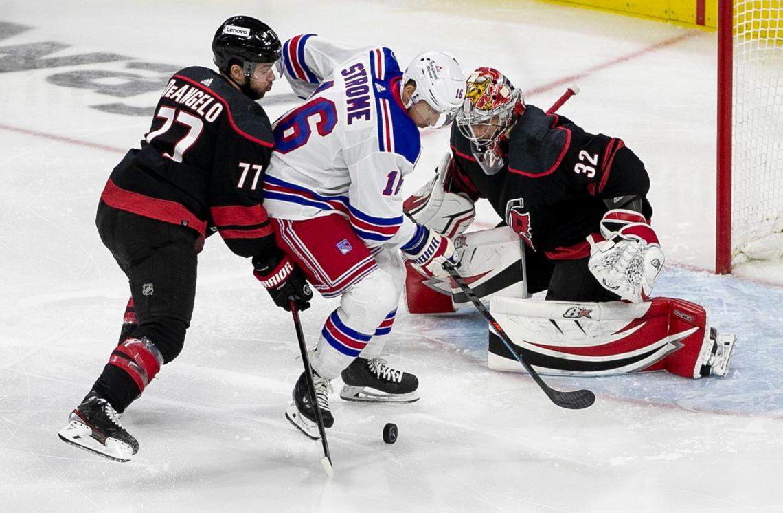 Carolina Hurricanes Tony DeAngelo (77) defends New York Rangers Ryan Strome (16) in front of Hurricanes goalie Antii Raanta (32) in the first period on Friday, May 20, 2022 during game two of the Stanley Cup second round at PNC Arena in Raleigh, N.C.