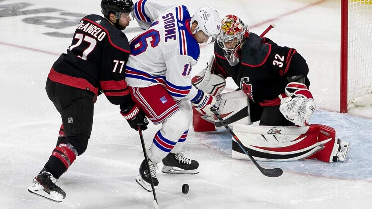Carolina Hurricanes Tony DeAngelo (77) defends New York Rangers Ryan Strome (16) in front of Hurricanes goalie Antii Raanta (32) in the first period on Friday, May 20, 2022 during game two of the Stanley Cup second round at PNC Arena in Raleigh, N.C.