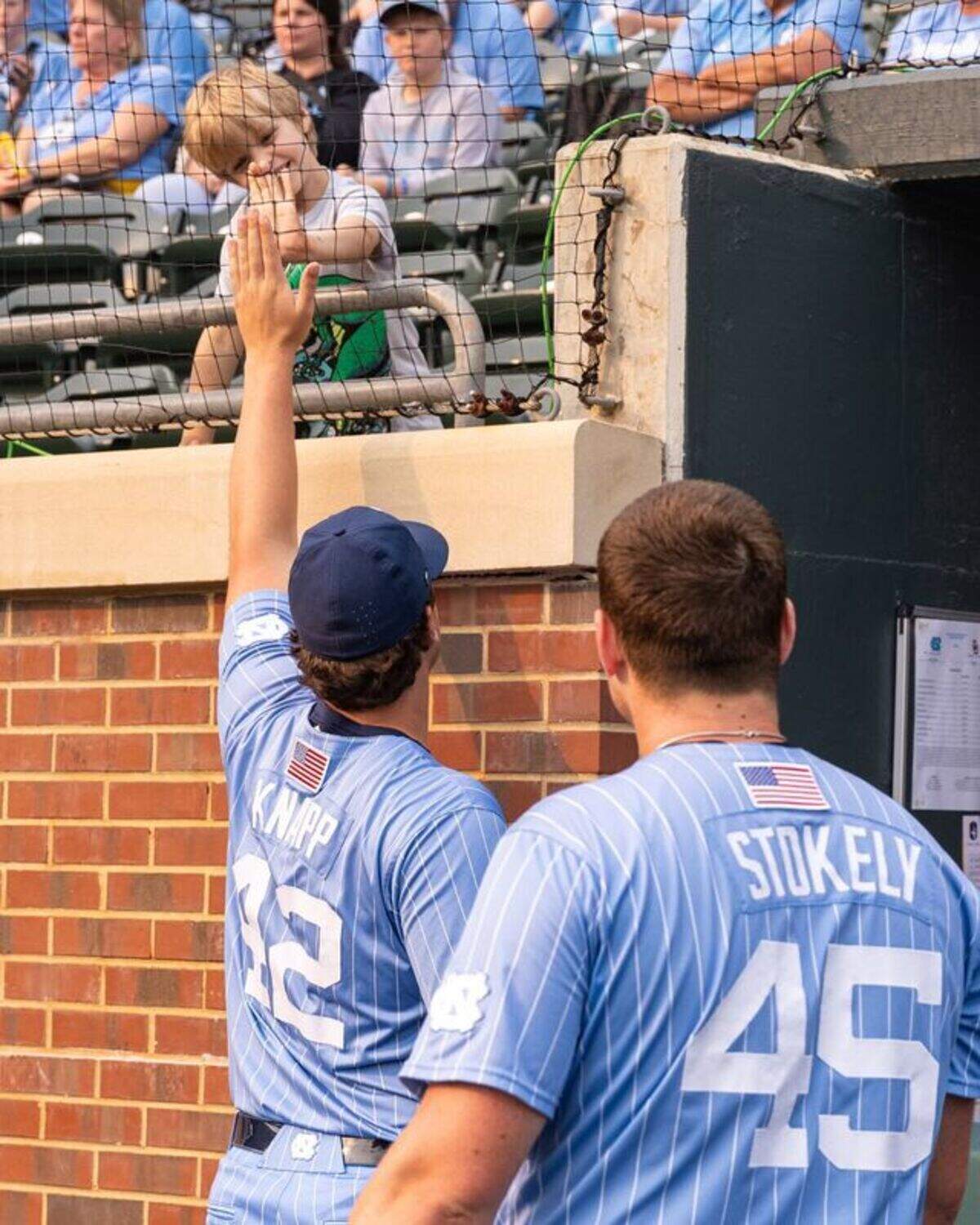 Former North Carolina baseball players Jake Knapp and Hunter Stokely greet David Hill during a game at Durham Bulls Athletic Park in Durham, North Carolina.
