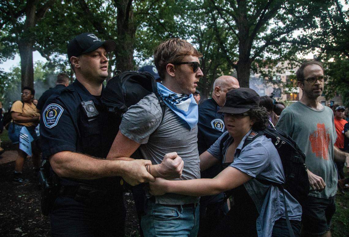 A protestor is led away by police as demonstrators cover the a Confederate statue known as Silent Sam with banners Monday, August 20, 2018 at UNC-Chapel Hill. Demonstrators surrounded and obscured the statue with large banners before toppling it.