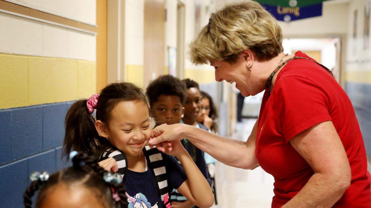 Fox Road Magnet Elementary teacher Dr. Linda Robinson, right, bends down to greet Jasmine Nguyen, left, on Wednesday morning, Sept. 11, 2019, during their daily “Gauntlet of Love” which has teachers and staff line the entrance and hallways to greet students as they arrive for another day of classes. It’s part of a culture of caring principal Bob Lewis credits for helping the school double its passing rate on state tests over the last seven years.