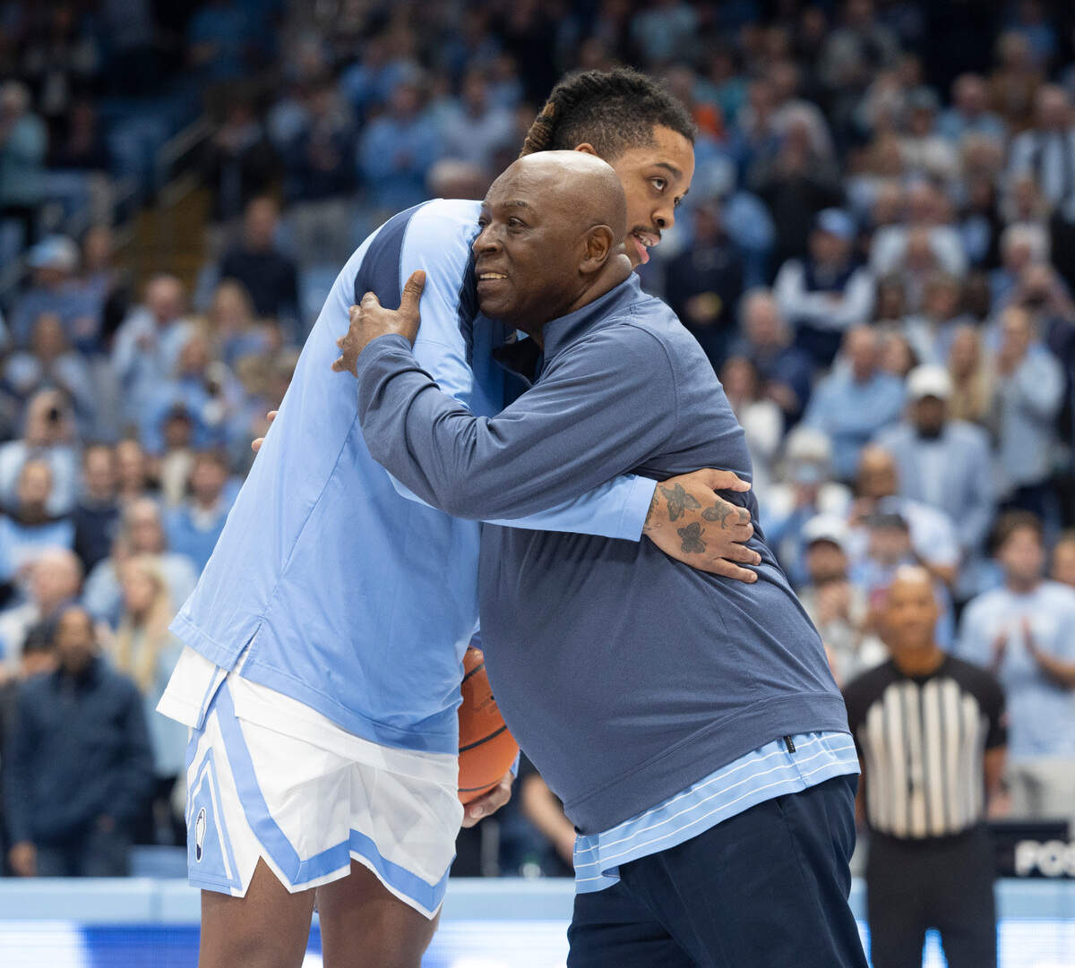 Former Tar Heel Phil Ford embraces Armando Bacot (5) after presenting him a game ball prior to North Carolina’s game against Syracuse on Saturday, January 13, 204 at the Smith Center in Chapel Hill, N.C. Bacot broke into the 2000 point scoring record book at North Carolina during the game at Pitt last week.