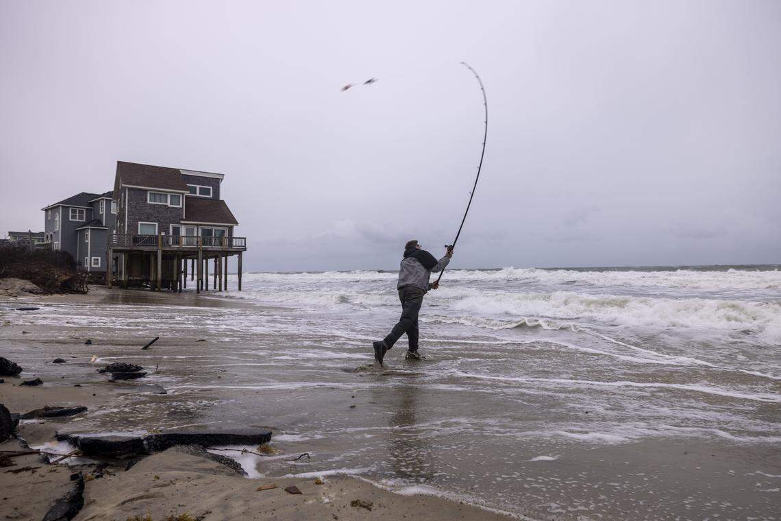 Brian Boak of Wayne, N.J., casts his line while fishing as rough surf threatens beach homes during high tide Saturday, Oct. 11, 2025, in Buxton as a nor’easter approaches the North Carolina coast. Nine homes in the community have collapsed into the Atlantic Ocean since mid-September.