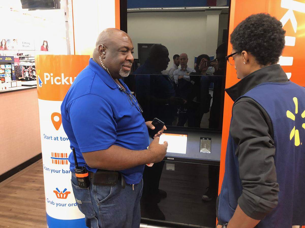 Kennedy Byrd, left, the department manager for online grocery and pickup at the Walmart on New Bern Avenue in Raleigh, demonstrates loading packages into Walmart’s new Pickup Tower. The towers are located near the front of participating Walmart stores and can hold hundreds of items. Customers scan a code and pick up items they have previously ordered online, skipping customer service lines.