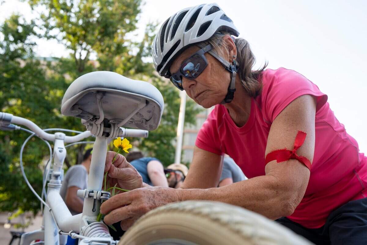 Ruth Browne attaches flowers to the white memorial bike at the annual Durham Ride of Silence honoring those killed or injured while biking at the CCB Plaza in Durham, N.C., on Wednesday, May 18, 2022.