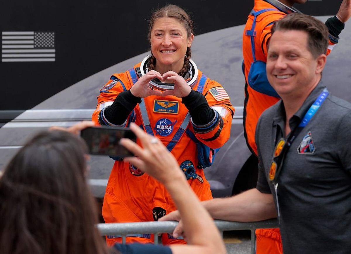 CAPE CANAVERAL, FLORIDA - APRIL 01: (L-R) Mission specialist Christina Koch flashes a heart sign with her hands and poses for photographs as she and fellow astronauts depart the Neil A. Armstrong Operations and Checkout Building ahead of the launch of the Artemis II at NASA's Kennedy Space Center on April 01, 2026 in Cape Canaveral, Florida. The 322-foot-tall Artemis II Space Launch System rocket and Orion spacecraft will take the astronauts around the moon and back, 230,000 miles out into space and the farthest any human has ever traveled from Earth. (Photo by Chip Somodevilla/Getty Images)