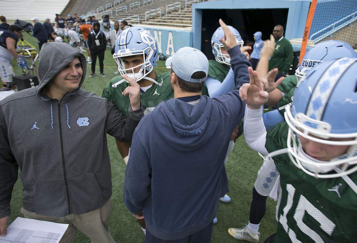 Tommy Hatton, left, huddles with the North Carolina quarterbacks at the start of practice in March 2018 in Chapel Hill.
