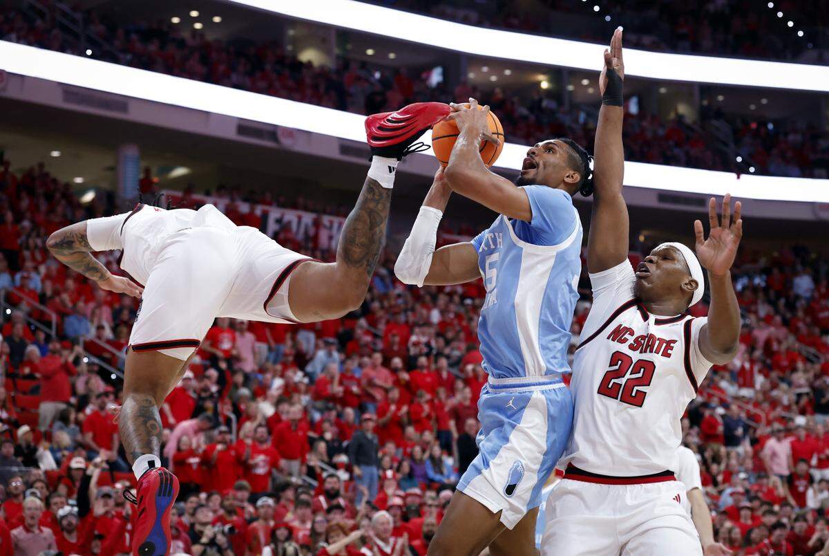 North Carolina's Jarin Stevenson drives to the basket against N.C. State's Darrion Williams and Ven-Allen Lubin in first half action.  Williams left the game with an injury to the face after hitting the floor hard, but returned to action before the half.