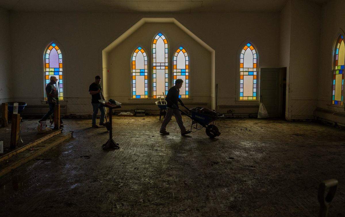 Johnny Bolick, a member of IChurch from Hickory, N.C., pushes a wheel barrow of debris from the sanctuary of Old Fort United Methodist Church on Saturday, October 5, 2024 in Old Fort, N.C. More than four feet of water from Mill Creek flooded the building during Hurricane Helene.