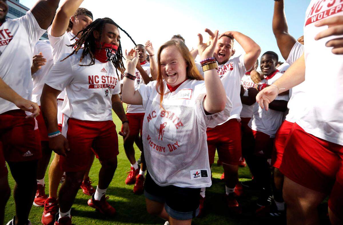 Megan Czejkowski of Raleigh celebrates scoring a touchdown with N.C. State football players during “Victory Day” with the Wolfpack at Carter-Finley Stadium in Raleigh, N.C., Saturday, August 7, 2021. The Wolfpack partnered with GiGi’s Playhouse Raleigh, a Down’s syndrome achievement center, to let participants enjoy a game day experience with players.