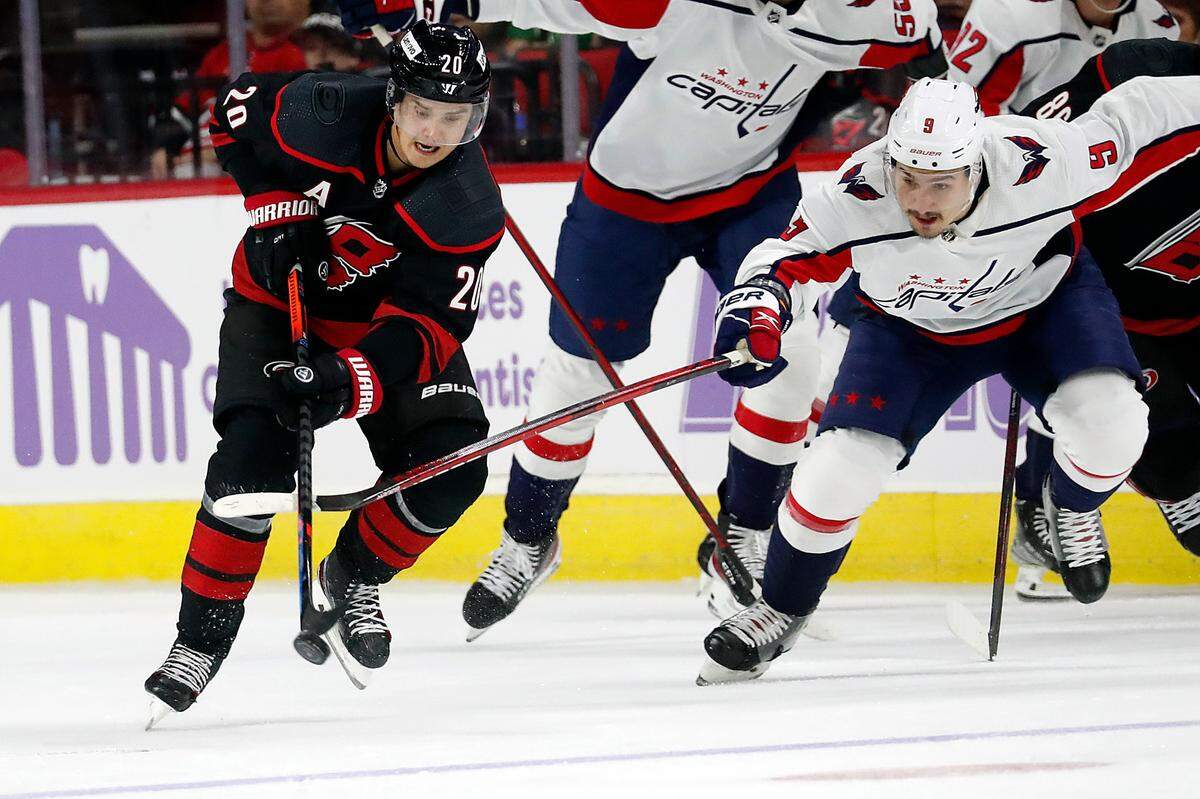 Washington Capitals’ Dmitry Orlov (9) tries to poke the puck away from Carolina Hurricanes’ Sebastian Aho (20) during the second period of an NHL hockey game in Raleigh, N.C., Sunday, Nov. 28, 2021. (AP Photo/Karl B DeBlaker)