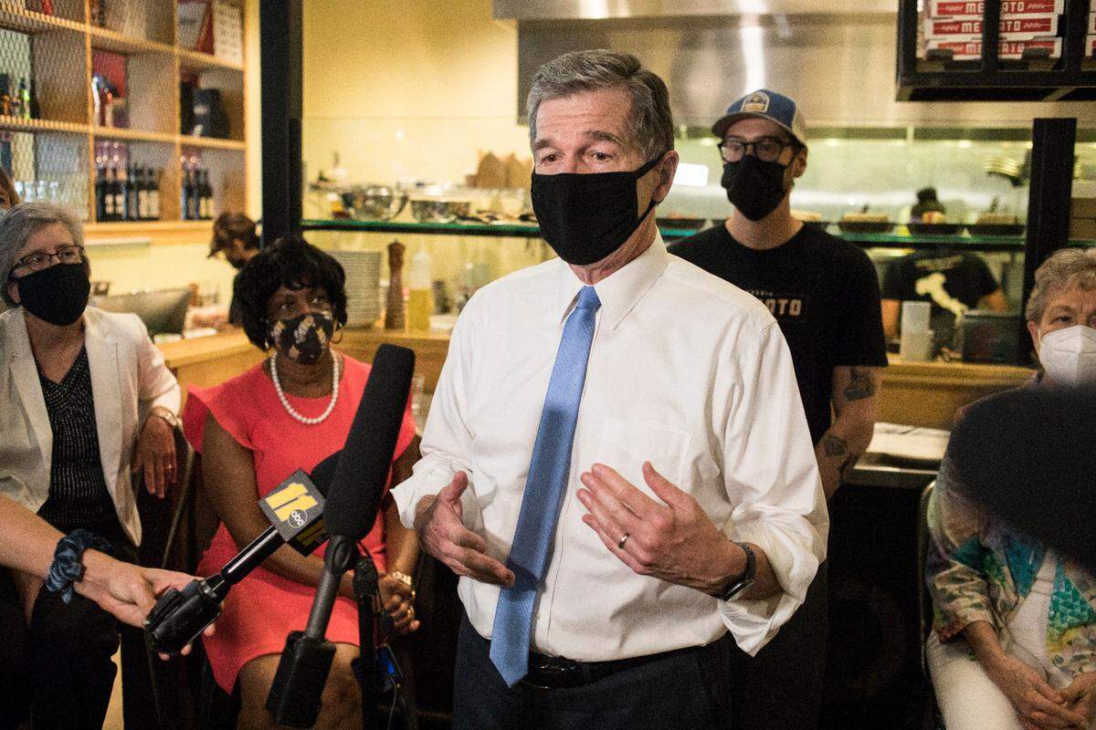 Gov. Roy Cooper speaks to the press during a visit to Pizzeria Mercato, a restaurant in Carrboro, N.C. that requires guests to show proof of vaccination, on Thursday, Aug. 26, 2021.