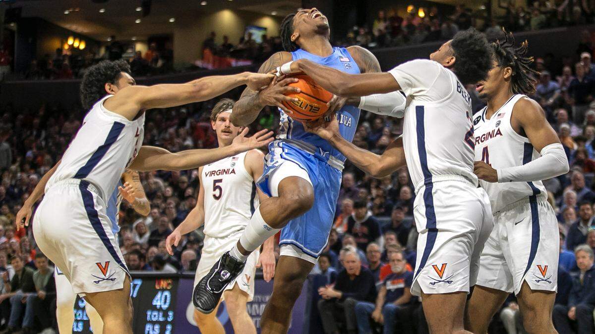 Virginia’s Kihei Clark (0) and Reece Beekman (2) stop North Carolina’s Caleb Love (2) as he drives to the basket in the second half on Tuesday, January 10, 2023 at John Paul Jones Arena in Charlottesville, Va. Virginia defeated North Carolina 65-58.
