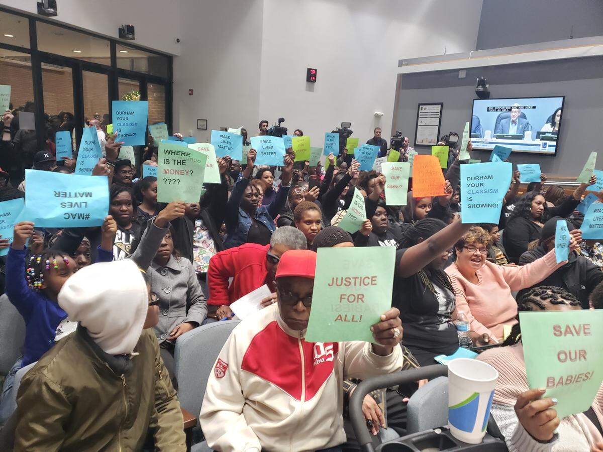 Durham Housing Authority residents and supporters hold up signs at the Durham City Council meeting on Jan. 6, 2019. Residents at the meeting expressed outrage about the conditions of their apartments and carbon monoxide concerns.