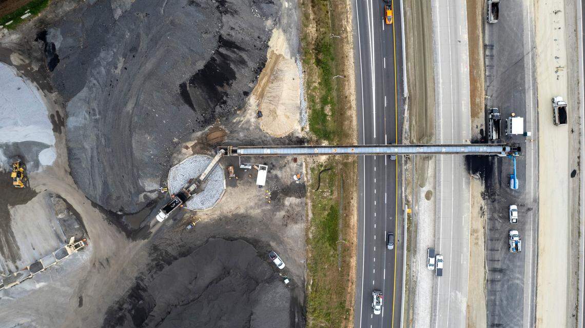 A conveyor system carries asphalt over the eastbound lanes of I-40 near the N.C. 42 interchange in Garner on Wednesday, Sept. 27, 2023. The conveyor will move about 175,000 tons of asphalt from its plant off Cleveland Road in the coming months, enough to pave 5 miles of eight-lane highway.