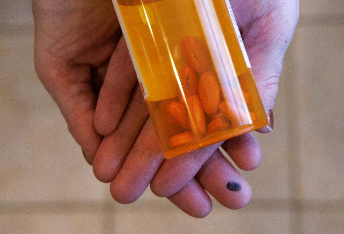 Tiffanie Brinson holds a bottle of her son’s mood stabilizing medication at their home in Garner, N.C. on Monday, Jan. 22, 2024. When her son, who lives with autism and bipolar disorder, is experiencing a psychiatric crisis, she and her husband get him to his bedroom, which has been cleared of hard objects and outfitted with calming activities.