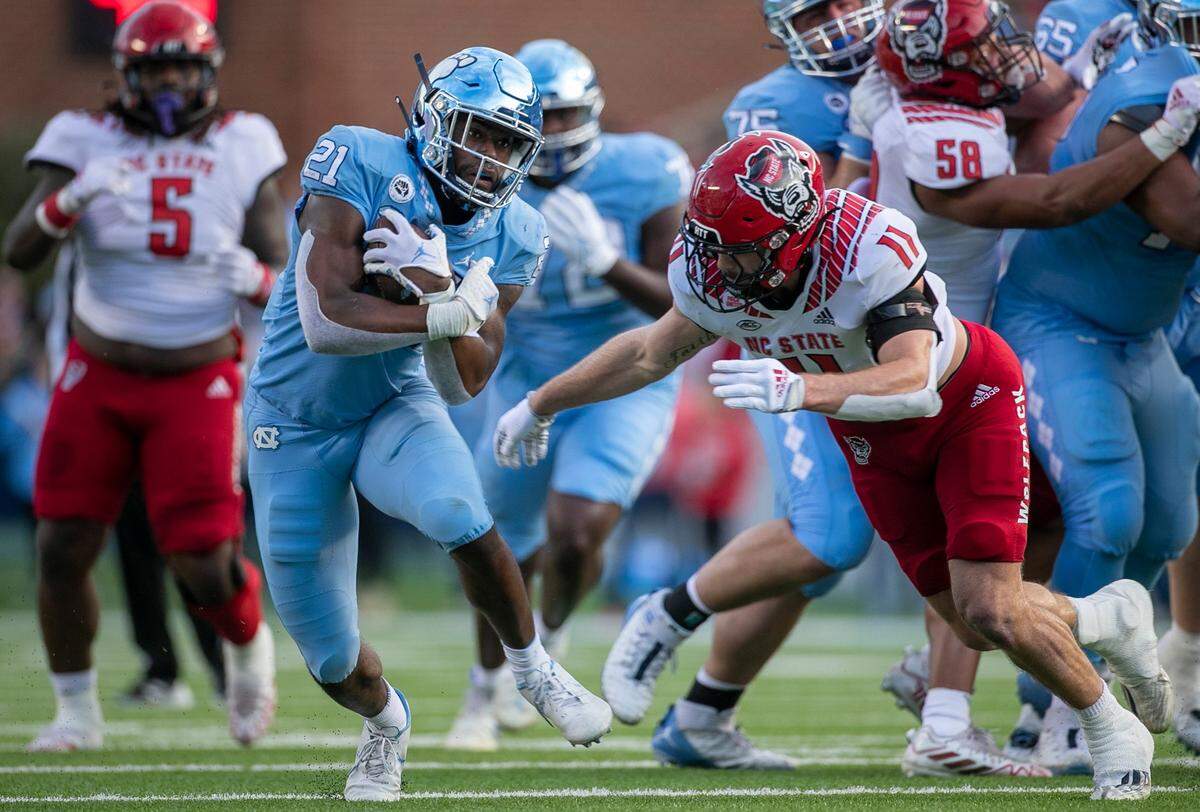 North Carolina’s Elijah Green (21) picks up 11 yards in the first quarter against N.C. State’s Payton Wilson (11) on Friday, November 25, 2022 at Kenan Stadium in Chapel Hill, N.C.