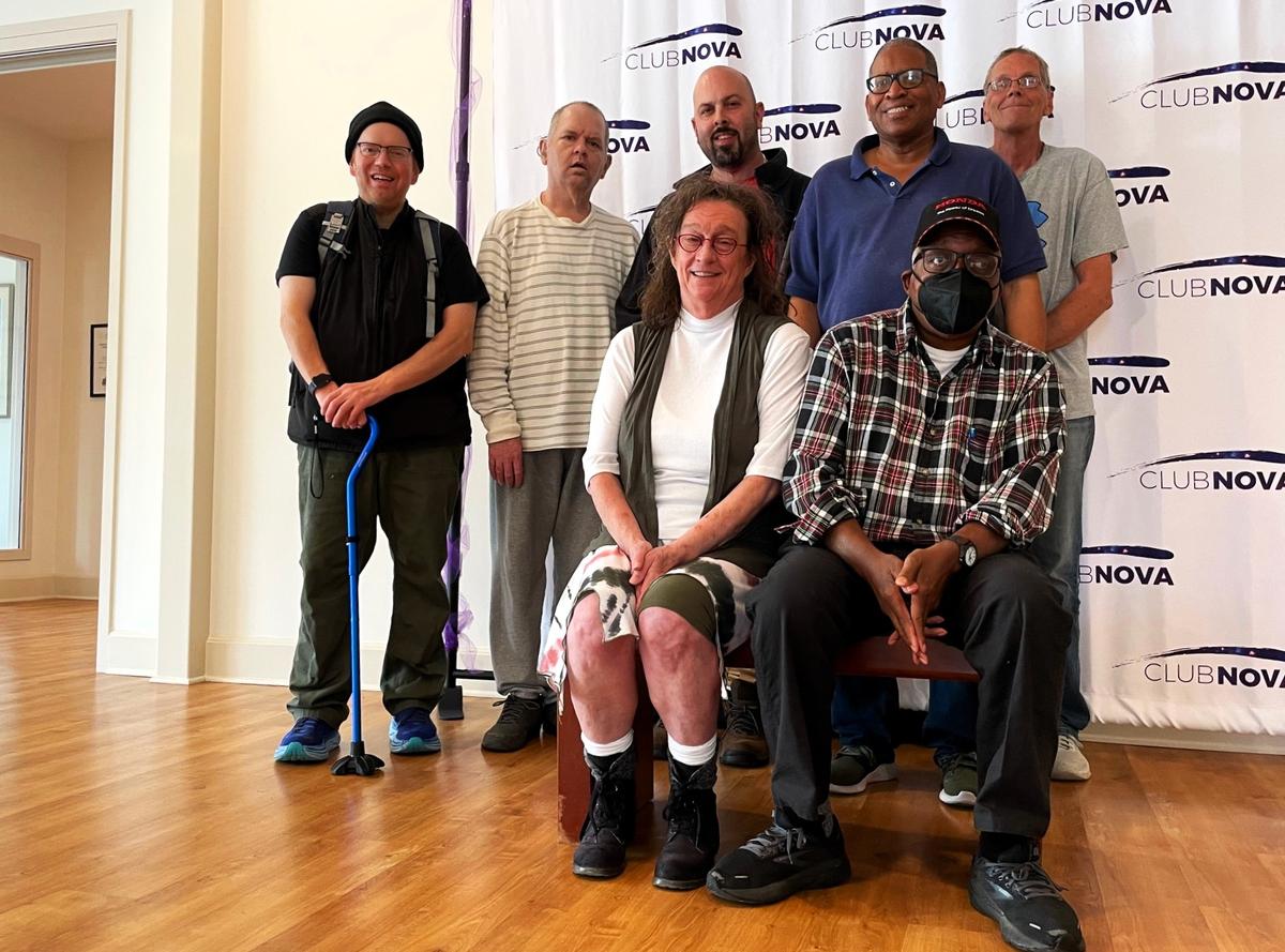 Club Nova’s Executive Director Karen Kincaid Dunn stops for a photo Monday, Nov. 11, 2024, with a group of longtime members, also known as “colleagues.” The nonprofit Clubhouse provides support and assistance to people living with several mental illness.
