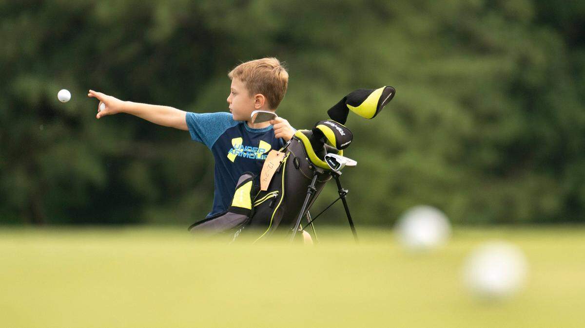 8-year-old Ethan Leeman tosses a golf ball while practicing golf with his dad, Dan Leeman, at 401 Par Golf in Raleigh, N.C. on Thursday, Aug. 18, 2022. Developers are planning to buy the 72 acres that 401 Par Golf sits on and build a master-planned residential and commercial community.
