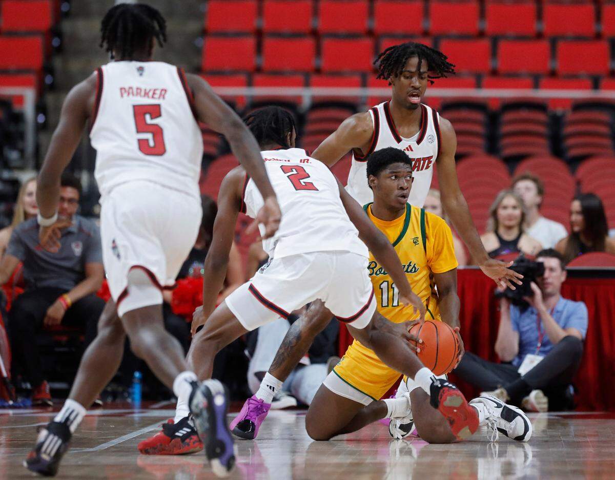 Lees-McRae’s Ja’Quavian Florence looks to pass beyond pressure from N.C. State’s Paul McNeil, Jr. and Bryce Heard during the first half of the Wolfpack’s 79-75 exhibition win on Wednesday, Oct. 30, 2024, at the Lenovo Center.