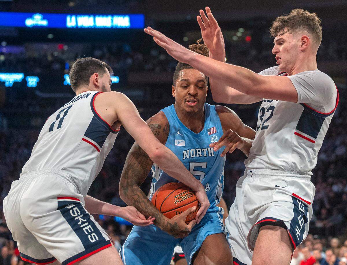 Connecticut’s Alex Karaban (11) and Donovan Clingan (32) grab grab North Carolina’s Armando Bacot (5) during the second half in the Jimmy V Classic on Tuesday, December 5, 2023 at Madison Square Garden in New York, NY.