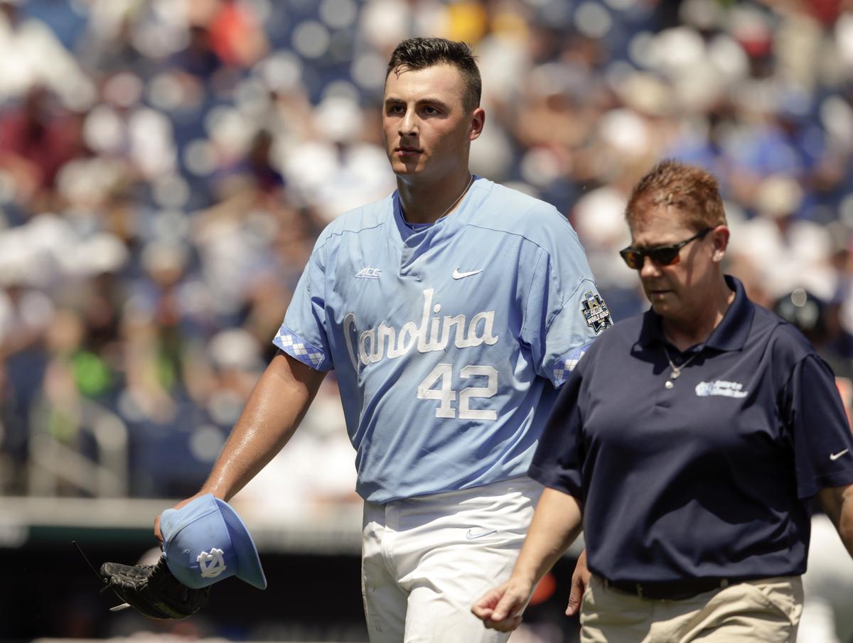 North Carolina pitcher Gianluca Dalatri (42) is escorted off the field following an injury in the first inning of an NCAA College World Series baseball game against Oregon State in Omaha, Neb., Saturday, June 16, 2018.
