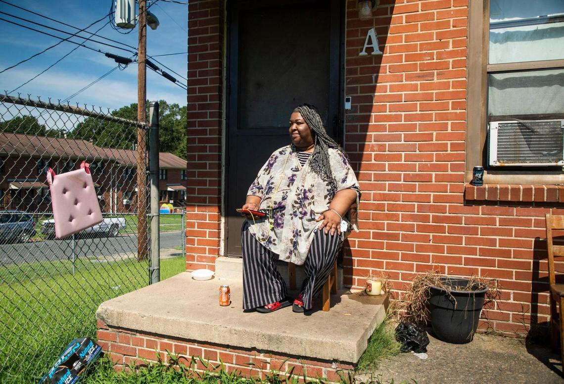 Tanya Kelley sits for a portrait on her porch after describing the previous night’s shootings that occurred across the street from her home that police say injured five people and killed one person at McDougald Terrace, and on nearby Linwood Avenue, on Thursday, Aug. 19, 2021, in Durham, N.C.
