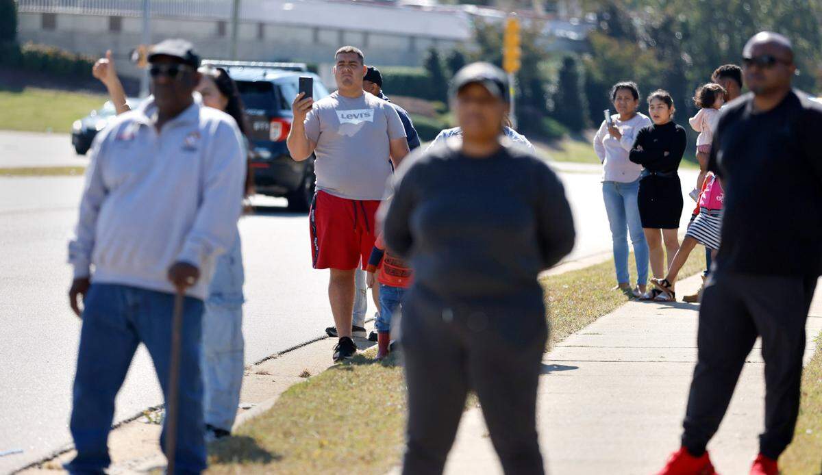 People watch as a funeral procession for Raleigh Police Officer Gabriel Torres passes them on New Bern Ave. while on its way to Brown-Wynne funeral home in Raleigh Saturday, Oct. 22, 2022. Officer Torres was killed in a mass shooting Oct. 13