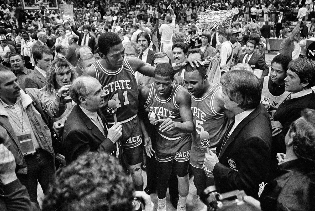 CBS announcer Billy Packer, left, interviews N.C. State seniors Thurl Bailey, Dereck Whittenburg, and Sidney Lowe after the Wolfpack won the National Championship on April 4, 1983. The Wolfpack knocked off top-ranked Houston, 54-52.