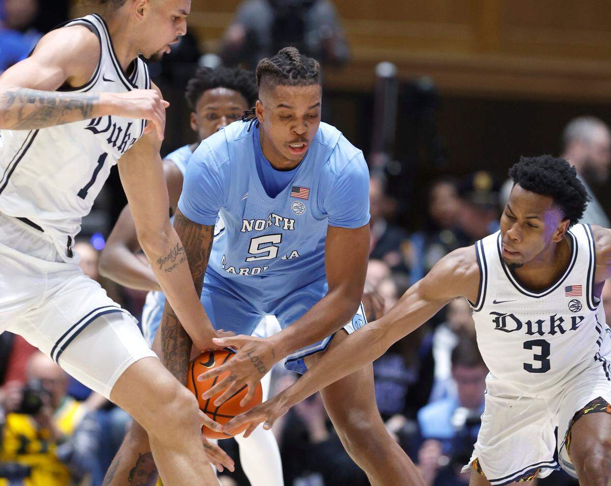North Carolina’s Armando Bacot (5) gets the ball from Duke’s Dereck Lively II (1) and Jeremy Roach (3) during the first half of Duke’s game against UNC at Cameron Indoor Stadium in Durham, N.C., Saturday, Feb. 4, 2023.