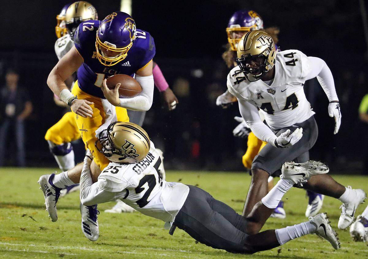 East Carolina’s Holton Ahlers (12) gets taken down by Central Florida’s Kyle Gibson (25) with Nate Evans (44) closing during the first half of an NCAA college football game in Greenville, N.C., Saturday, Oct. 20, 2018. (AP Photo/Karl B DeBlaker)
