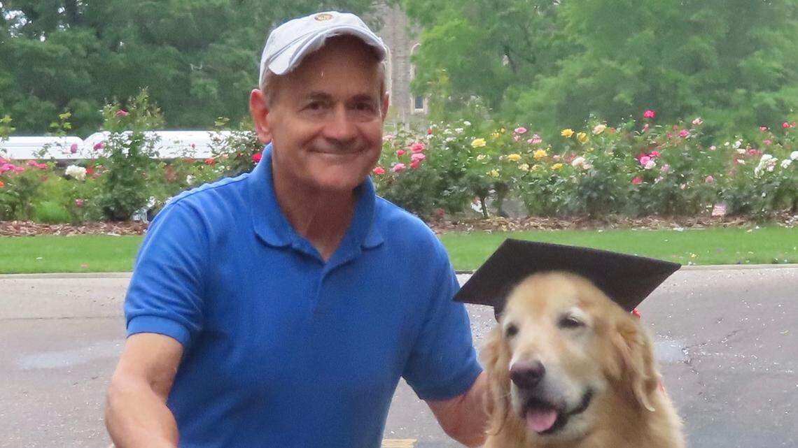 Golden retriever, Nugget, and her owner Keith Upchurch pose outside the Duke University Chapel before graduation day in May 2022.
