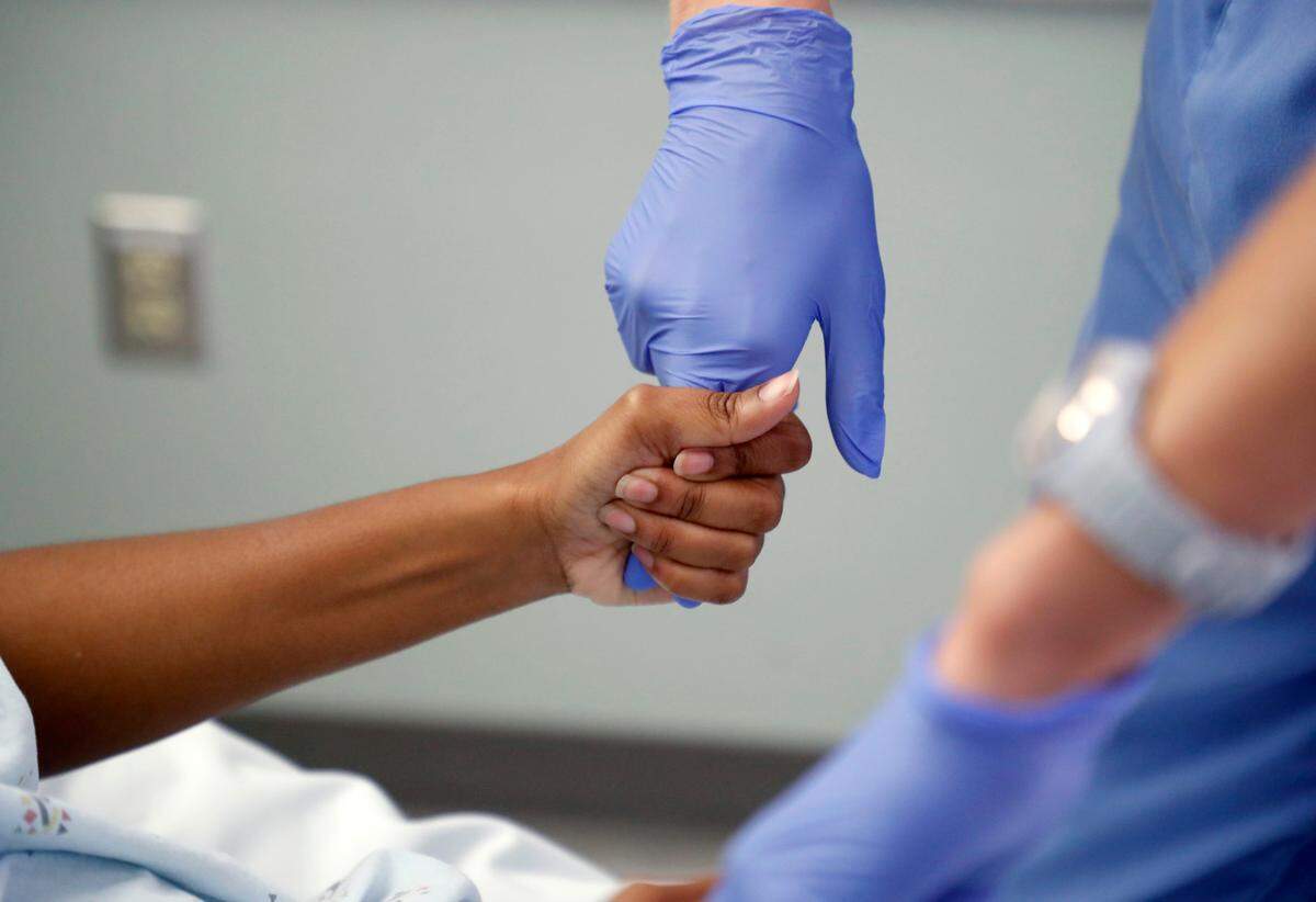 Erica South, a nurse in the emergency department, has DeTyah Cook squeeze her hands while checking on her at UNC REX Hospital in Raleigh, N.C., Friday, October 1, 2021.