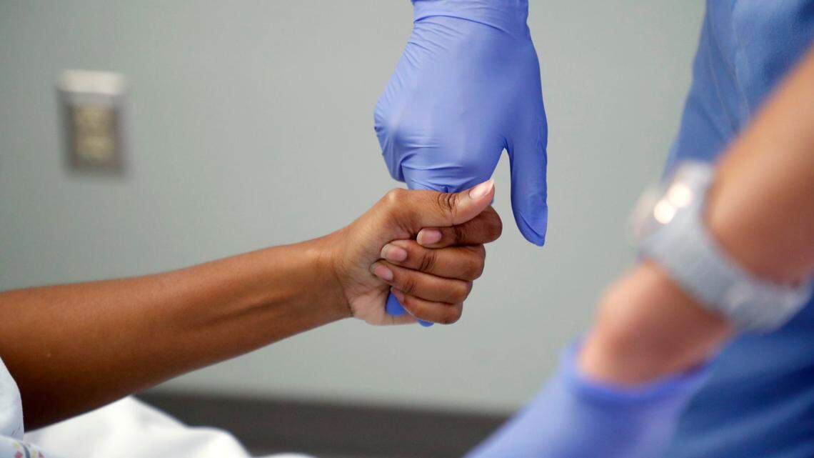 Erica South, a nurse in the emergency department, has DeTyah Cook squeeze her hands while checking on her at UNC REX Hospital in Raleigh, N.C., Friday, October 1, 2021.