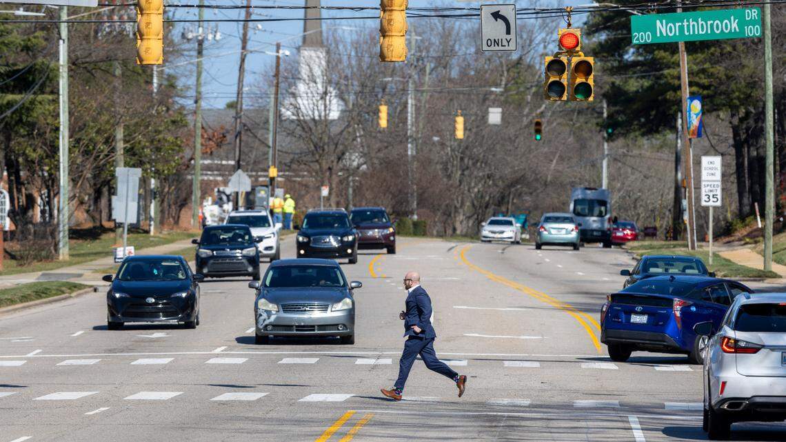 A pedestrian crosses Six Forks Road at the intersection of Northbrook Drive on Wednesday, February 21, 2024 in Raleigh, N.C. The Raleigh City Council has approved improvements to this segment of Six Forks Road between Carroll Middle School and Millbrook Road that will widen the street to three travel lane and add a median The project includes construction of bike and pedestrian lanes on each side of the road.