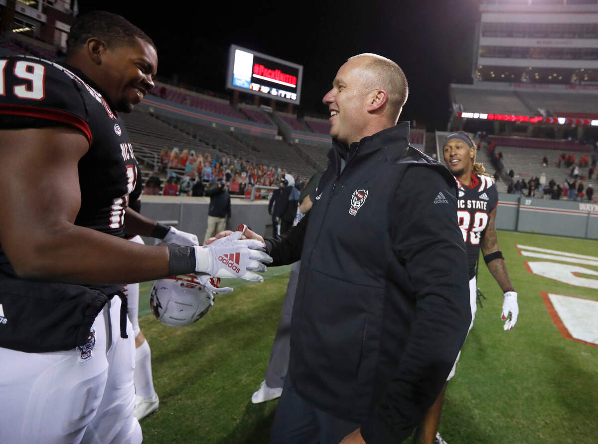 N.C. State head coach Dave Doeren celebrates with wide receiver C.J. Riley (19) after N.C. State’s 23-13 victory over Georgia Tech at Carter-Finley Stadium in Raleigh, N.C., Saturday, Dec. 5, 2020.