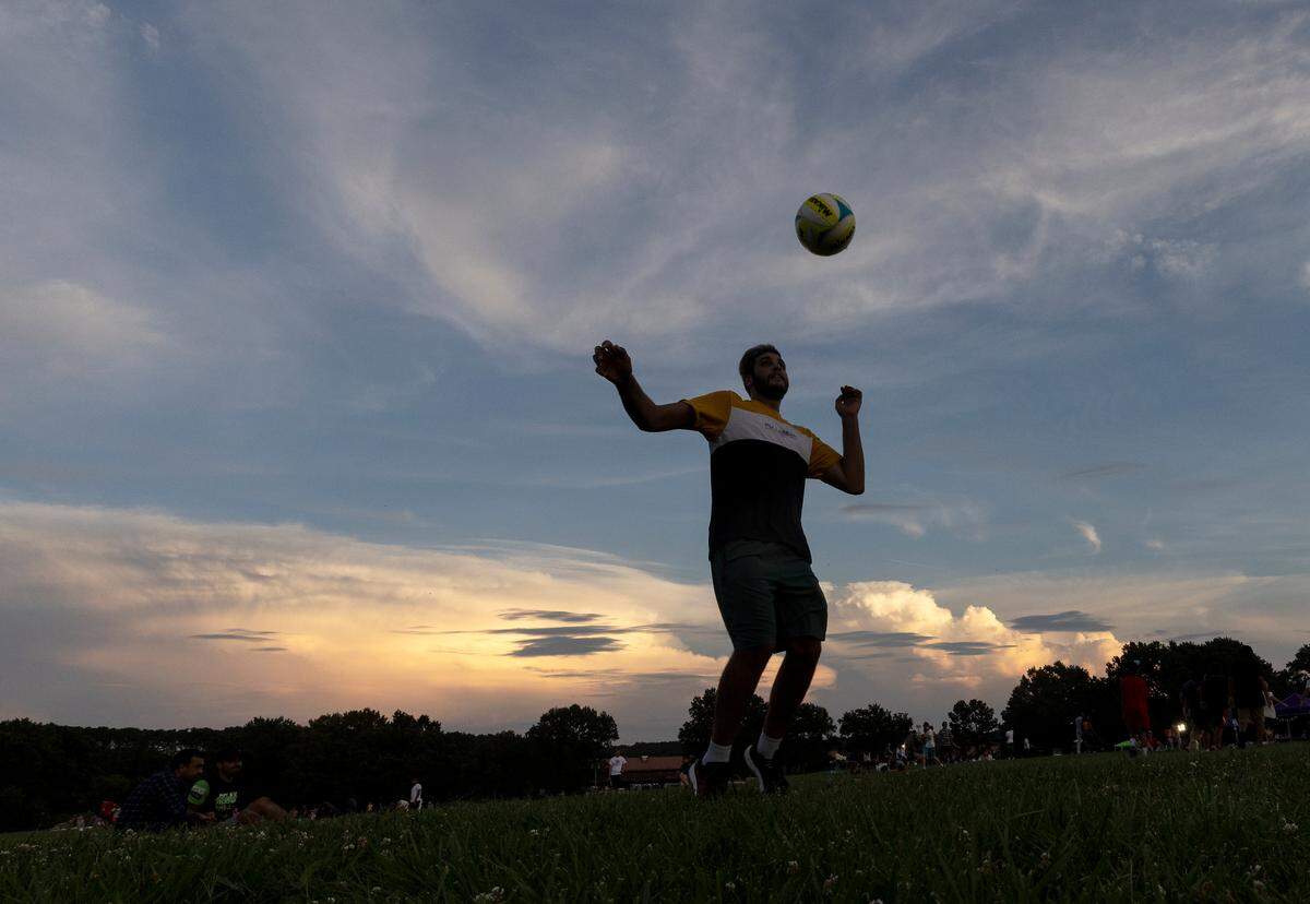A person plays with a soccer ball as the sun sets during an Independence Day celebration at Dorothea Dix Park on Tuesday, July 4, 2023, in Raleigh, N.C.