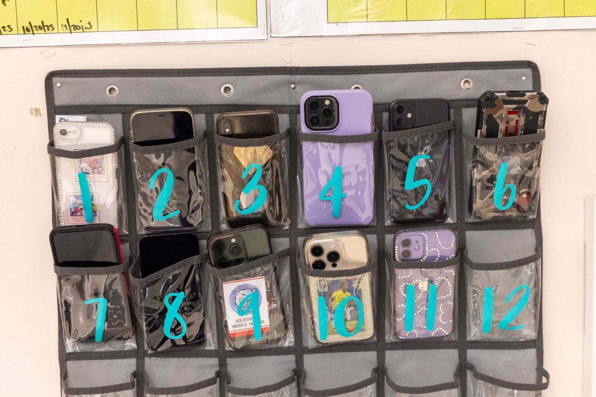 Phones sit in a caddy in a seventh-grade classroom at Rolesville Middle School on Wednesday, March 27, 2024.