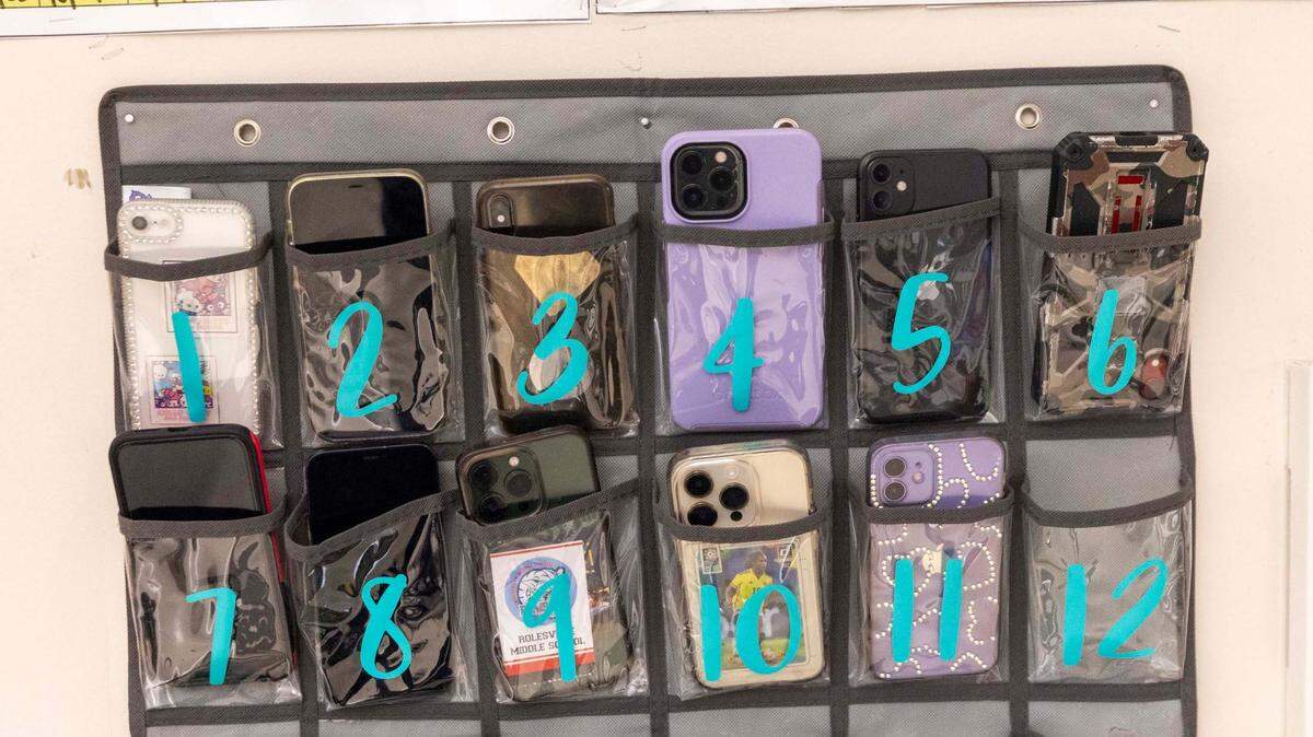 Phones sit in a caddy in Kyanna McCall’s seventh-grade classroom at Rolesville Middle School on Wednesday, March 27, 2024.